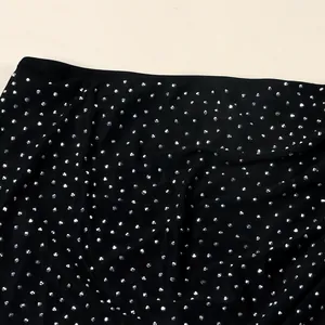 Primer plano de tela negra con detalles de pedrería plateada brillante.
