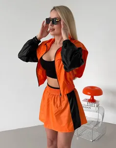 Model showcasing a bright orange and black two-piece sporty set with a matching mini skirt