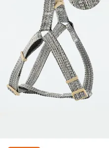 Detail shot of a grey and white woven dog harness featuring adjustable tan plastic buckles
