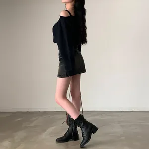 Vista laterale di un maglione nero con spalle scoperte abbinato a una minigonna di jeans