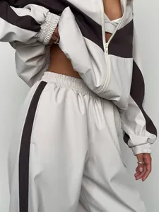 Detailed view of women's two-piece tracksuit with contrast stripes and zip-up jacket