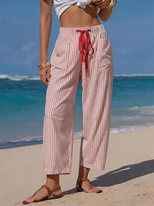 Casual pink striped wide-leg pants with red drawstring on a sunny beach setting