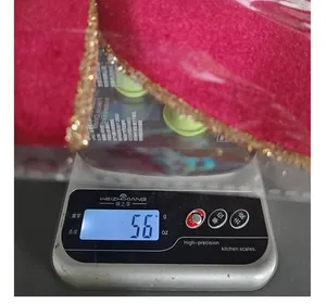 Close-up detail showing the lightweight 5.6g measurement of a glittery Christmas bow.