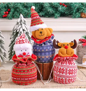 Detailopname van drie feestelijke gebreide kerstcadeautasjes met trekkoord en cartoonfiguren