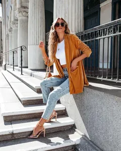 Detailed view of women's loose mustard yellow velvet coat in an urban street setting