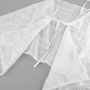 Gros plan sur les broderies florales complexes et la dentelle ajourée du caraco blanc