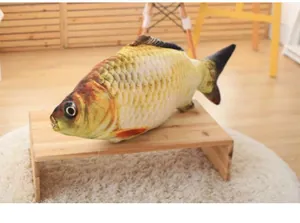 Realistic fish-shaped plush cat toy with catnip placed on a natural wooden stool.