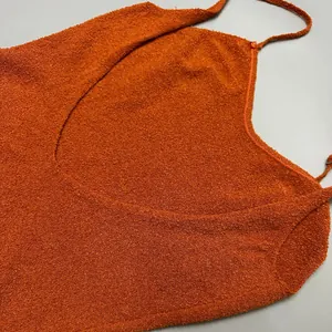 Close-up view of textured orange knit fabric and thin straps on a backless summer dress.