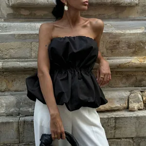 Detailed shot of a stylish black strapless peplum top paired with elegant white trousers.