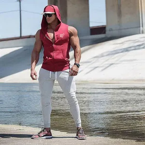 Detail view of a muscular man wearing a red sleeveless fitness gym hoodie by the water