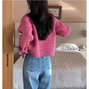 Achteraanzicht van een chique roze gebreid vest gecombineerd met een blauwe spijkerbroek