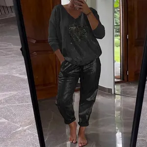 Detail of two-piece dark grey casual set with golden print long sleeve top and pants