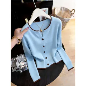 Detailed close-up of a light blue knitted cardigan featuring brown trim and buttons.