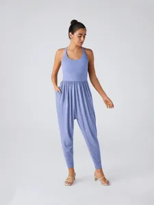 Women's chic sleeveless blue jersey jumpsuit with tapered legs and elastic waist design.
