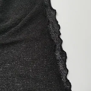 Macro view of black transparent knitted mesh fabric with detailed scalloped lace edge.