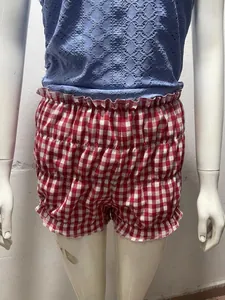 Close-up detail of red and white gingham women's shorts with cute ruffles on mannequin.