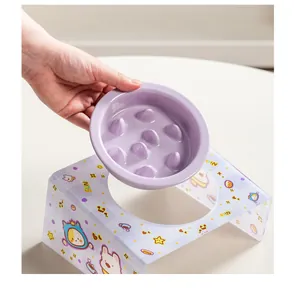 Close-up of hand holding a purple ceramic slow feeder bowl above a cute acrylic pet stand
