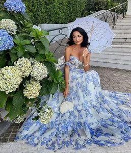 Detailed view of an elegant off-shoulder floral organza evening gown in a garden