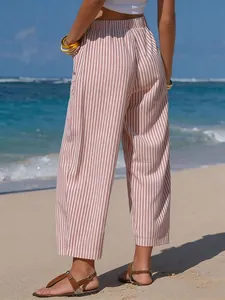 Detailed back view of women's striped faux linen cropped pants on a sunny summer beach