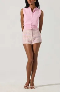 Detail view of a pink sleeveless knit button-up vest paired with tweed shorts