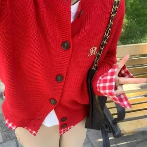 Détail rapproché d'un cardigan rouge avec revers à carreaux et logo PB brodé élégant