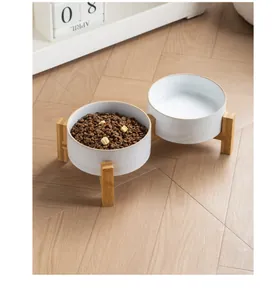 Primer plano de cuencos de cerámica minimalistas en soporte de bambú con comida y agua.