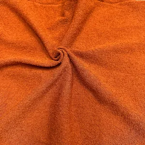 Close-up of burnt orange knit fabric texture with subtle sparkle for vacation dress