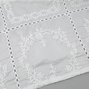 Détail montrant des broderies anglaises blanches complexes et des motifs floraux en coton