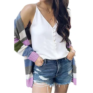 Modelo luce un cárdigan de punto a rayas multicolores sobre una camisola blanca con cuello en V