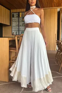 Detail of white high-waisted wide-leg pants featuring a stylish tassel fringe hem