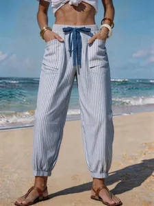 Detailed view of striped drawstring beach trousers in a sunny coastal setting