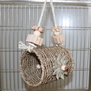Detail view of woven grass bird tunnel toy with wooden beads and palm leaf flower