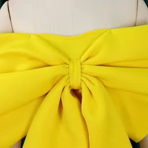 Dettaglio ravvicinato di un grande fiocco giallo su un top femminile a spalle scoperte