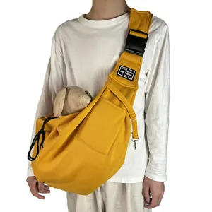 Breathable yellow pet sling carrier bag worn by a person for outdoor travel