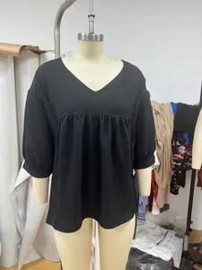 Detailansicht einer schwarzen V-Ausschnitt-Bluse mit Spitze und 3/4-Ärmeln an einer Puppe.