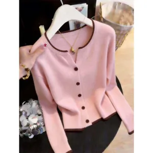 Close-up detail of a soft pink knitted cardigan featuring elegant brown contrast trim.