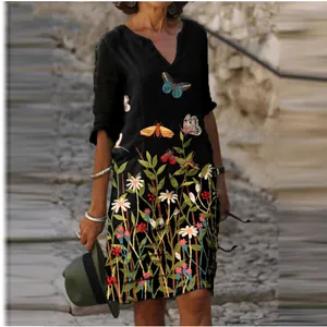 Model wearing black V-neck vintage dress with butterfly and floral prints outdoors