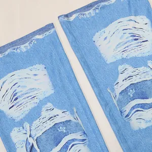 Détail d'un pantalon flare avec imprimé faux denim et motifs blancs artistiques.