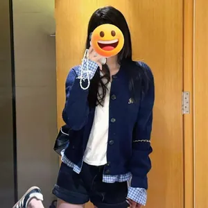 Vue détaillée d'un cardigan en maille bleu marine avec poignets et ourlet à carreaux superposés
