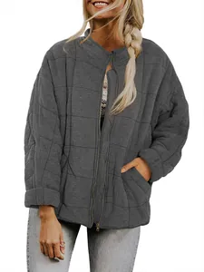 Detail view of women's loose grey quilted jacket with stand collar and gold zipper