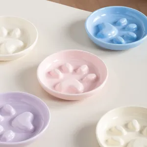 Assorted pastel paw-shaped ceramic slow feeder bowls for cats and dogs on a table