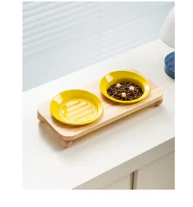 Zwei gelbe Keramik-Futternäpfe auf einem minimalistischen Ständer aus hellem Eichenholz