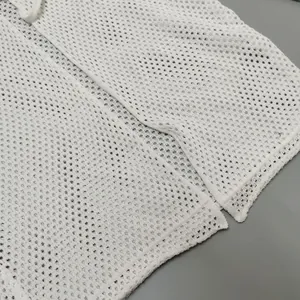 Detail view of white mesh knit cardigan showing intricate eyelet texture and hem