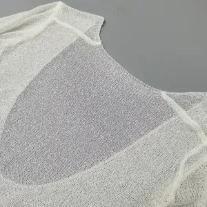 Close-up detail of white knitted hollow-out mesh fabric for a sexy beach cover-up dress
