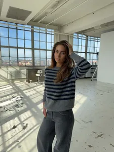 Modelo con un jersey de punto a rayas grises y azules en un estudio loft luminoso.