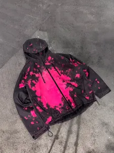 Detail view of a black waterproof hooded jacket featuring temperature-sensitive pink splatter pattern