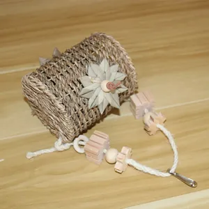 Detailed view of a woven straw bird nest with wooden hanging toys for parrots.