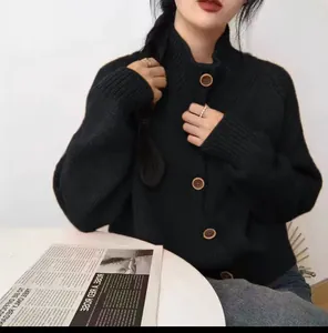 Detalle de una chaqueta de punto negra para mujer con cuello alto y botones grandes.