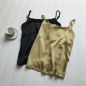 Dettaglio di eleganti canotte in raso con spalline sottili in nero e oro champagne.