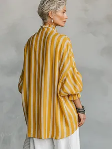 Perfil trasero de una mujer con camisa de rayas amarillas y puños con volantes elegantes.